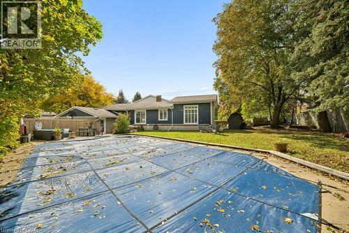 Backyard featuring an inground swimming pool with a safety cover, concrete surround, expansive lawn, and mature trees - 361 Lee Circle, Waterloo, ON 