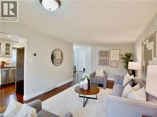 Neutral-toned interior featuring wood-finish flooring, ceiling-mounted light fixtures, and white cabinetry with stainless steel appliances - 449 Exmoor Street, Waterloo, ON 