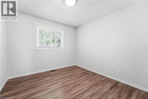 Room featuring wood-finish flooring, neutral wall paint, and a single-pane window with integrated blinds - 449 Exmoor Street, Waterloo, ON 