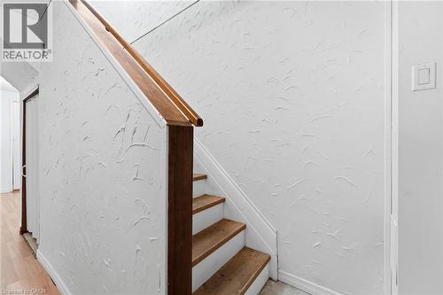 Staircase featuring wood-finish treads, a solid wood handrail, and textured wall finish - 449 Exmoor Street, Waterloo, ON 