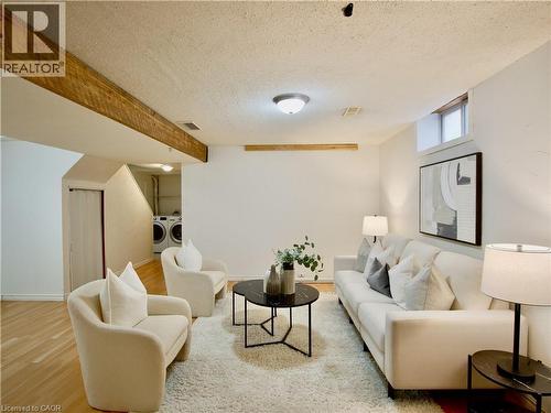 Open-concept interior featuring wood-finish flooring, exposed natural wood beams, and a high-mounted rectangular window - 449 Exmoor Street, Waterloo, ON 