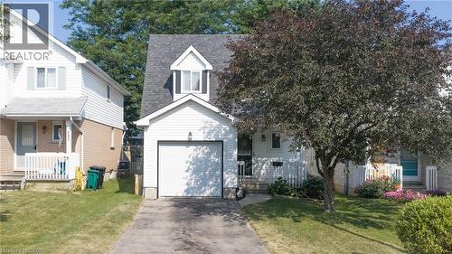 Two-story exterior featuring white vinyl siding, a front-facing single-car garage, a steep-pitched roofline with a dormer window, and an asphalt driveway - 449 Exmoor Street, Waterloo, ON 