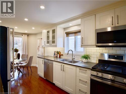 Kitchen featuring white cabinetry, subway tile backsplash, dark countertops, stainless steel appliances, and recessed lighting - 449 Exmoor Street, Waterloo, ON 