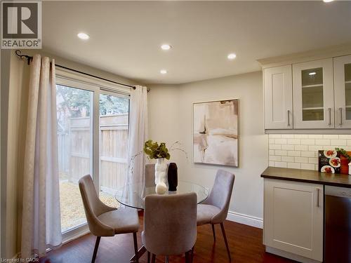 Shaker-style cabinetry with glass-panel upper doors, subway tile backsplash, sliding glass door, recessed lighting, and wood-finish flooring - 449 Exmoor Street, Waterloo, ON 