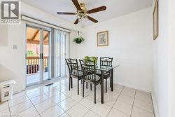 Neutral-toned tile flooring, sliding glass door with vertical blinds, and a brass-finished ceiling fan with integrated lighting - 
