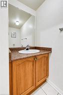 Wood-finish cabinetry featuring dual doors, stone-patterned countertop, integrated oval basin, chrome finish faucet, and wall-mounted mirror - 