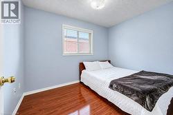 Room featuring wood-finish flooring, a single-pane window with white blinds, and a circular flush-mount ceiling light fixture - 