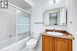 Bathroom featuring a tub-shower combination with sliding glass doors, wooden cabinetry, an oval drop-in sink, and a surface-mounted medicine cabinet - 