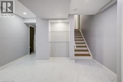 Large-format tile flooring, recessed ceiling lighting, built-in recessed shelving with glass tiers, and wooden staircase treads - 