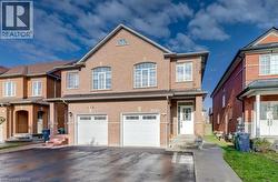 Two-story brick exterior featuring a double-car garage, arched window detailing, an arched transom window, and a paved private driveway - 