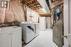 Utility space featuring white tile flooring, a white vanity cabinet with a basin sink, and a wall-mounted water filtration system - 