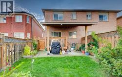Brick exterior with a covered patio, wood-post pergola, fenced rear yard, and lawn area - 