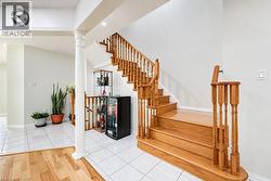 Staircase featuring wood treads and handrails with balusters, ceramic tile flooring, and a structural column - 