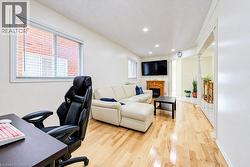 Wood-finish flooring, recessed lighting, natural light through multiple windows, and a built-in fireplace mantle - 