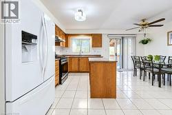 Kitchen featuring wood cabinetry, a center island with countertop, tile flooring, stainless steel range, and sliding glass doors - 