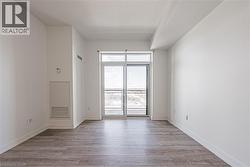 Wood-finish flooring, white walls, and a sliding glass door to a balcony - 