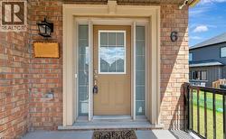 Exterior brick facade featuring a central entryway with a single-pane glass inset door and flanking sidelight windows, topped with a stone-finish lintel, finished with a wall-mounted outdoor lantern - 