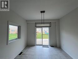 Tile flooring, geometric metal pendant lighting, and a glass sliding door providing access to a rear wood deck - 