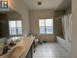 Bathroom featuring a single-sink vanity with a solid-surface countertop, tiled flooring, an oversized wall-to-wall mirror, and a built-in bathtub with a tiled surround - 
