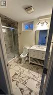 Bathroom featuring a walk-in shower with sliding glass doors, large-format patterned tile flooring, a white vanity with a stone countertop, an undermount sink, and a wall-mounted light fixture - 