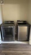 Dedicated laundry alcove featuring stainless steel top-load washer and matching dryer, set upon tile flooring - 