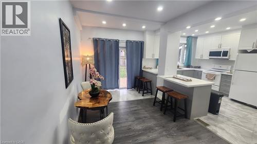 Kitchen featuring white cabinetry, quartz countertops, a central breakfast bar, recessed lighting, and tile flooring - 1394 Cannon Street E, Hamilton, ON 