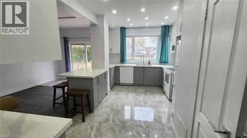 Kitchen featuring gray and white shaker-style cabinetry, quartz countertops, a matching central island, stone-finish tile flooring, and recessed ceiling lighting - 1394 Cannon Street E, Hamilton, ON 