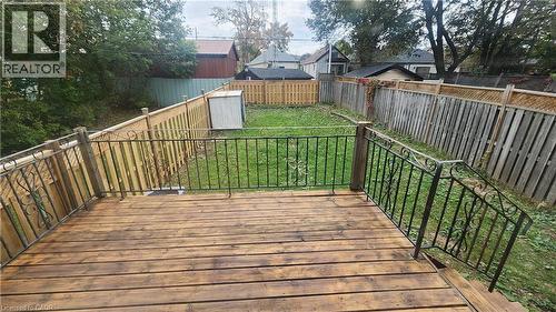 Elevated wooden deck featuring metal railings with scrollwork details, overlooking a fenced backyard - 1394 Cannon Street E, Hamilton, ON 