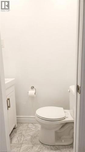 White cabinetry vanity with a clean-lined sink, wall-mounted toilet, and patterned tile flooring - 1394 Cannon Street E, Hamilton, ON 