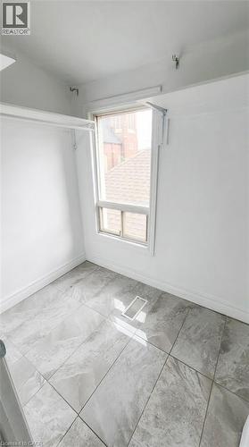 Storage space featuring large-format tile flooring and white wall-mounted shelving - 1394 Cannon Street E, Hamilton, ON 