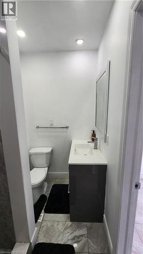 Modern vanity with integrated rectangular sink and solid surface countertop, dark-finish cabinetry, recessed ceiling lighting, and large-format tile flooring - 1394 Cannon Street E, Hamilton, ON 