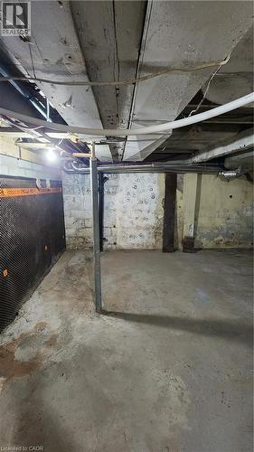 Unfinished lower level featuring concrete flooring, exposed ceiling joists, masonry block walls, and an integrated structural support column - 1394 Cannon Street E, Hamilton, ON 