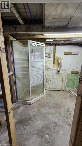 Corner shower unit with white frame, frosted glass panels, and exposed structural framing - 1394 Cannon Street E, Hamilton, ON 
