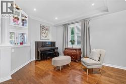 Tray ceiling with recessed lighting, wood-finish flooring, plantation shutters, crown molding, and decorative columns - 