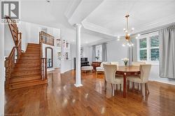 Hardwood flooring, staircase with carved wood railing, tray ceilings, decorative column, and modern multi-arm chandelier - 