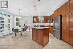 Kitchen featuring wood cabinetry, a central island with a stone countertop, stainless steel appliances, a mosaic tile backsplash, and recessed and pendant lighting - 
