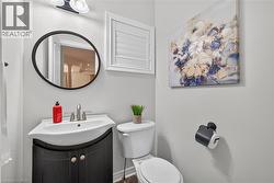 Curved dark wood-finish vanity with integrated sink, oval wall-mounted mirror, brushed nickel faucet, and louvered wall shutter - 