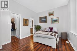 Interior room featuring dark wood-finish flooring, high ceilings, neutral wall tones, and a built-in walk-in closet with shelving - 