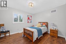 Room featuring wood-finish flooring, white plantation shutters, and a central flush-mount light fixture - 