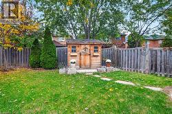 Backyard featuring a wooden storage shed, stone foundation elements, stepping stone path, and wood privacy fencing - 