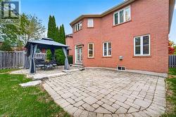 Full-brick exterior featuring a stone-paved patio, manicured lawn, and perimeter wood fencing - 