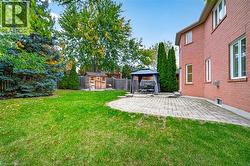 Brick exterior, stone patio, wooden storage structure, and fenced perimeter featuring mature landscaping - 