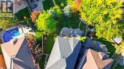 Aerial perspective of the property featuring a private swimming pool, stone-paver patio, expansive green space, and mature trees - 