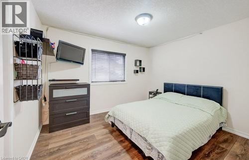 Bedroom featuring wood-finish flooring, a window with horizontal blinds, and a dome-style flush-mount ceiling light fixture - 521 Snowdrop Court, Kitchener, ON 