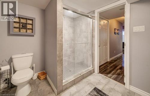Walk-in shower with glass enclosure, tiled surround, and mosaic tile flooring, featuring light gray wall finishes and ceramic floor tiling - 521 Snowdrop Court, Kitchener, ON 