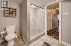 Walk-in shower with glass enclosure, tiled surround, and mosaic tile flooring, featuring light gray wall finishes and ceramic floor tiling - 
