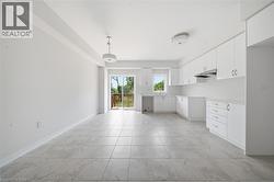 Kitchen featuring white cabinetry, solid-surface countertops, tile flooring, and sliding glass doors leading to an exterior deck - 