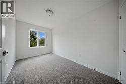 Neutral-toned carpeting, crisp white walls, dual-pane window with outdoor scenery, and flush-mount ceiling lighting - 
