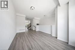 Interior space featuring wood-finish flooring, neutral walls, flush-mount ceiling lighting, and a staircase with a wooden handrail - 