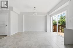 Neutral-toned tiled flooring, sliding glass doors, wooden exterior deck, recessed wall alcove, and a drum-style pendant light fixture - 